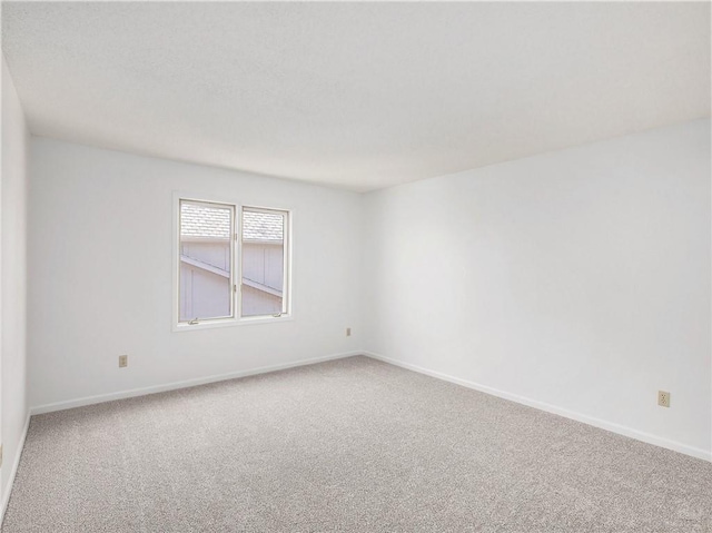 carpeted empty room featuring baseboards