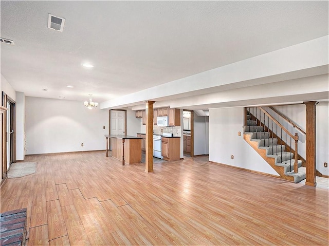 basement featuring visible vents, light wood-style floors, baseboards, a chandelier, and stairs