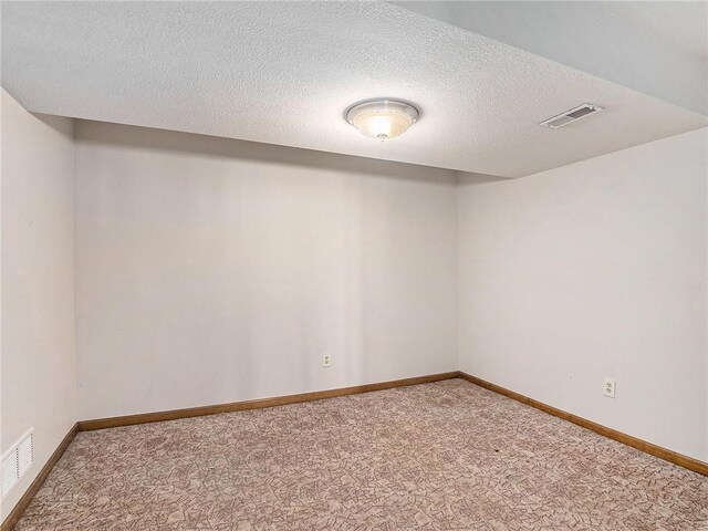 carpeted empty room with visible vents, a textured ceiling, and baseboards