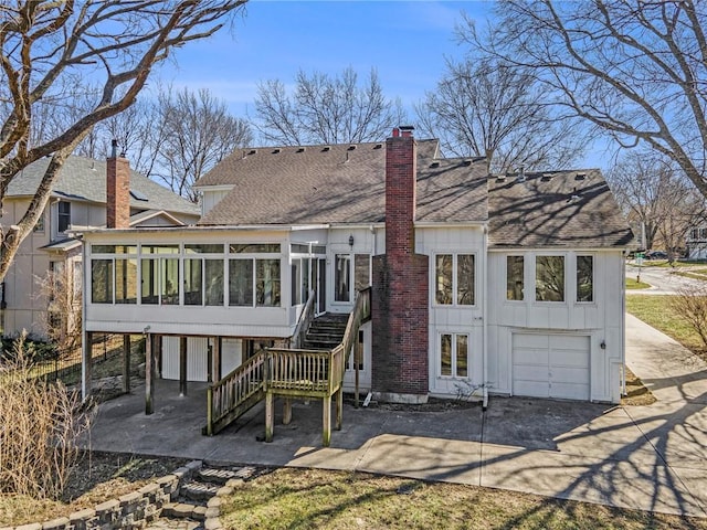 rear view of property with stairway, a shingled roof, a garage, and a sunroom