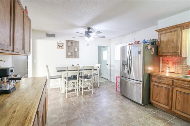 kitchen with wood counters, visible vents, backsplash, and stainless steel fridge with ice dispenser