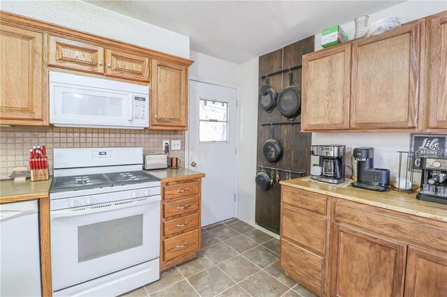 kitchen with light tile patterned floors, a textured ceiling, white appliances, light countertops, and backsplash