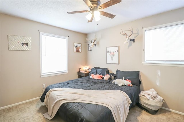 carpeted bedroom with ceiling fan, multiple windows, and baseboards