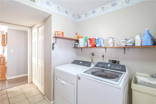 washroom featuring laundry area, light tile patterned flooring, a sink, and washing machine and clothes dryer