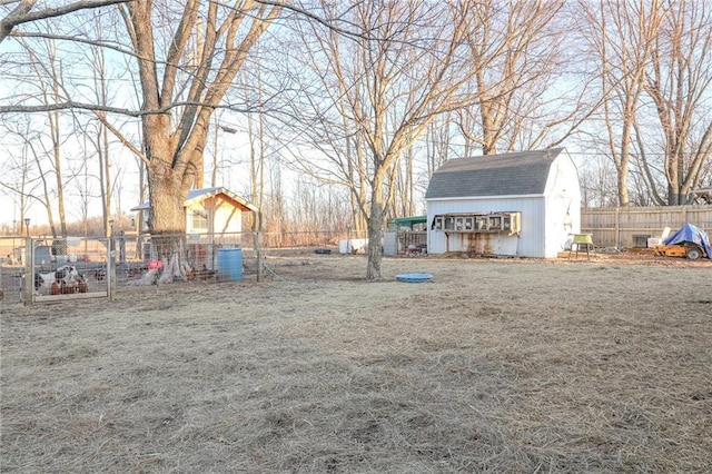 view of yard with an outdoor structure, a shed, and fence