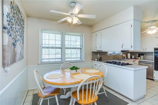 dining area featuring light tile patterned flooring, a wainscoted wall, and ceiling fan