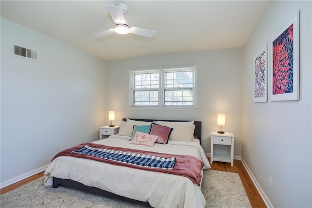 bedroom featuring a ceiling fan, wood finished floors, visible vents, and baseboards