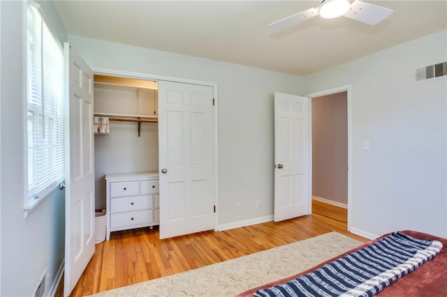 unfurnished bedroom with a ceiling fan, wood finished floors, visible vents, baseboards, and a closet