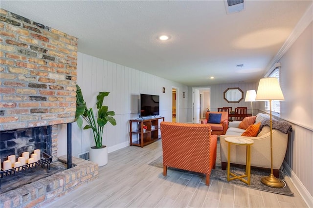 living area featuring wood finished floors, visible vents, recessed lighting, a fireplace, and a textured ceiling