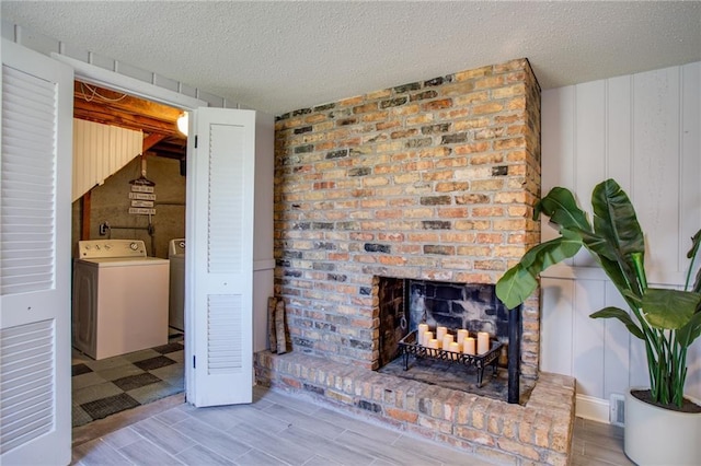 living area featuring visible vents, a textured ceiling, wood finished floors, separate washer and dryer, and a brick fireplace