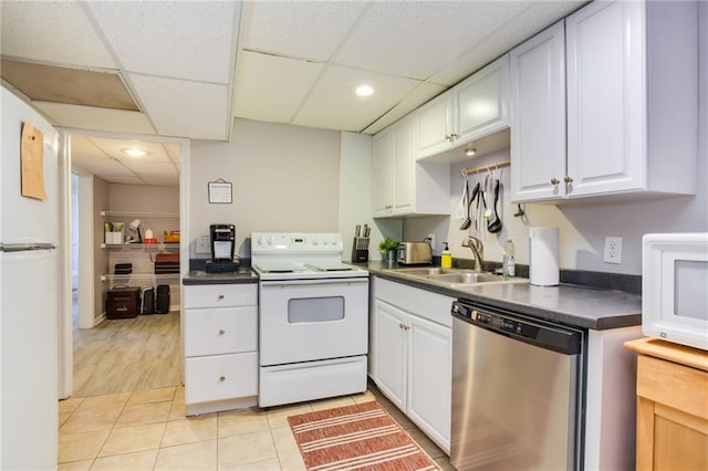 kitchen featuring white appliances, light tile patterned floors, a sink, white cabinets, and dark countertops