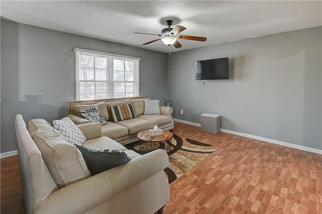 living area featuring baseboards, a textured ceiling, wood finished floors, and a ceiling fan