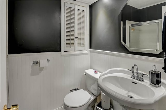 full bathroom featuring a stall shower, toilet, wainscoting, and a sink