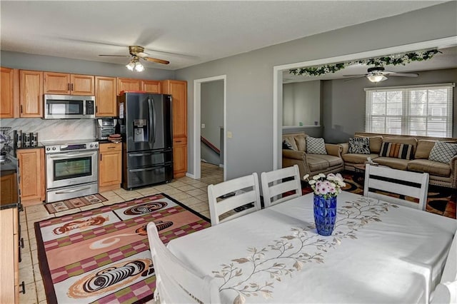 kitchen with dark countertops, tasteful backsplash, open floor plan, appliances with stainless steel finishes, and a ceiling fan