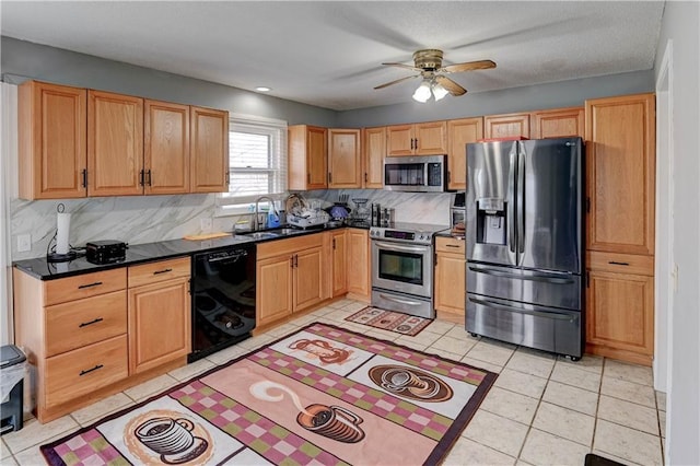 kitchen featuring dark countertops, backsplash, light tile patterned floors, appliances with stainless steel finishes, and a sink