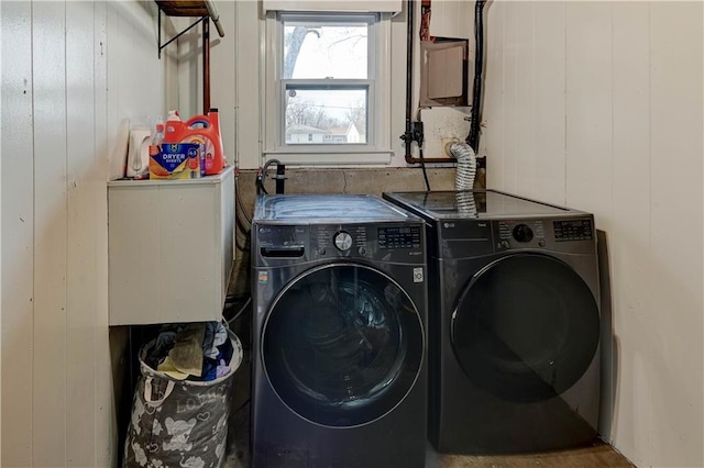 laundry room with laundry area, wood walls, and washer and clothes dryer