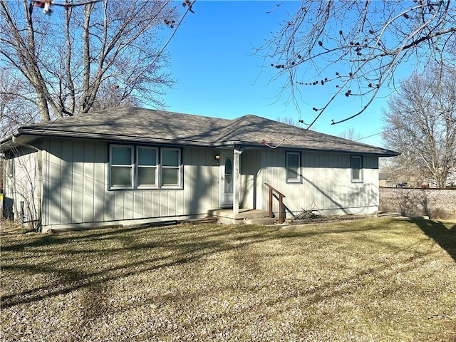 back of property featuring a yard and roof with shingles