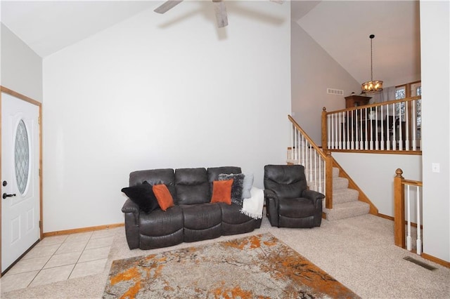 tiled living area featuring visible vents, ceiling fan with notable chandelier, high vaulted ceiling, and baseboards