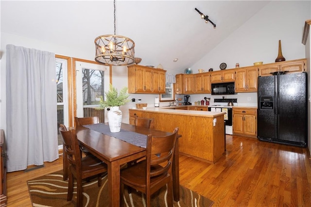 dining area featuring high vaulted ceiling, an inviting chandelier, wood finished floors, and rail lighting