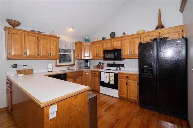 kitchen with black appliances, a peninsula, dark wood finished floors, and light countertops