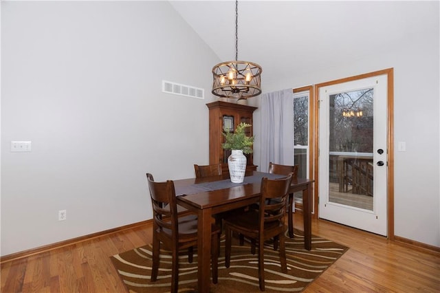 dining area with visible vents, baseboards, light wood-style floors, a notable chandelier, and high vaulted ceiling