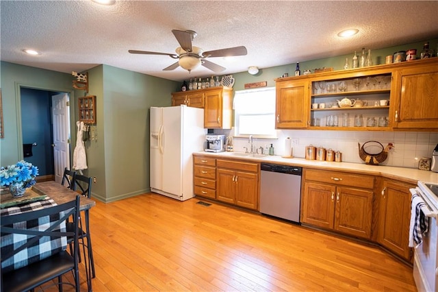 kitchen with white refrigerator with ice dispenser, light countertops, stainless steel dishwasher, a sink, and range