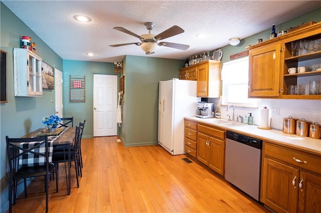 kitchen featuring open shelves, a sink, light countertops, stainless steel dishwasher, and white fridge with ice dispenser