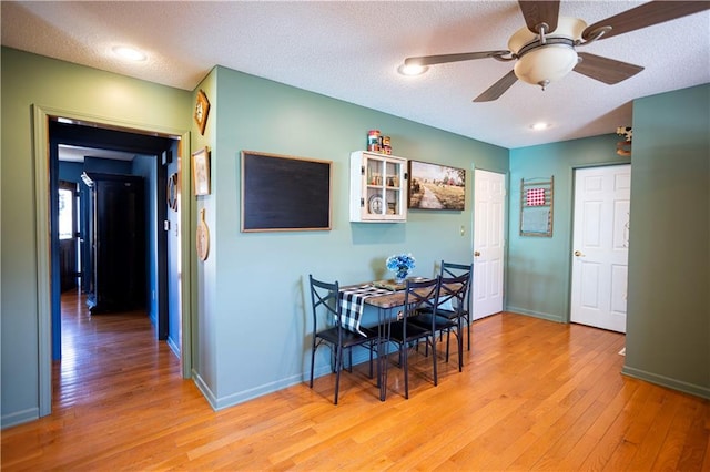 dining space featuring a ceiling fan, baseboards, a textured ceiling, and light wood finished floors