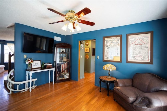 living area featuring baseboards, a ceiling fan, and wood finished floors