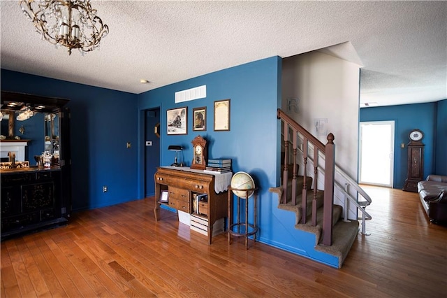 interior space featuring a textured ceiling, a fireplace, visible vents, and wood finished floors