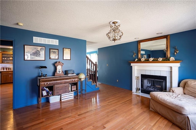 living room featuring visible vents, stairway, wood finished floors, a textured ceiling, and a fireplace