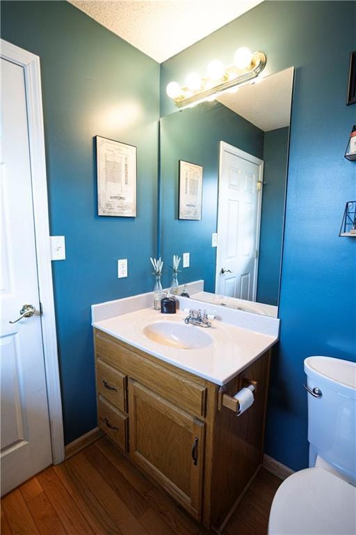 bathroom featuring baseboards, vanity, toilet, and wood finished floors