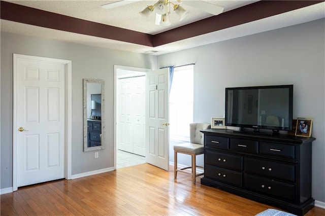 bedroom featuring a textured ceiling, ceiling fan, light wood-style flooring, and baseboards