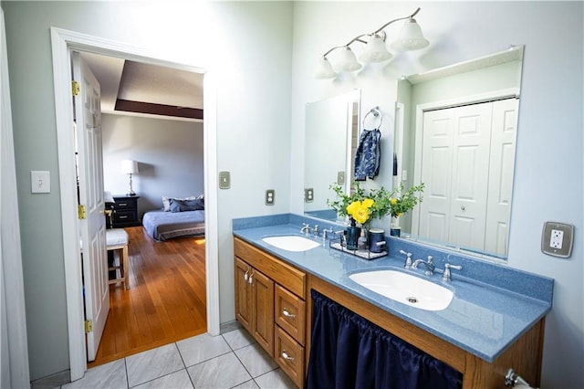 bathroom with connected bathroom, double vanity, a sink, and tile patterned floors