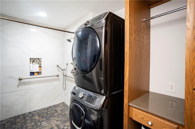 clothes washing area featuring stacked washer / drying machine and laundry area