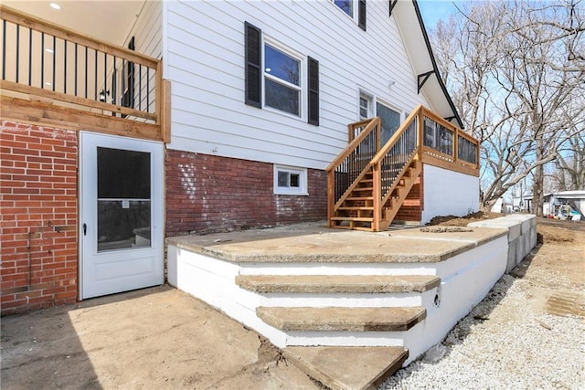 exterior space featuring stairs, brick siding, and a wooden deck