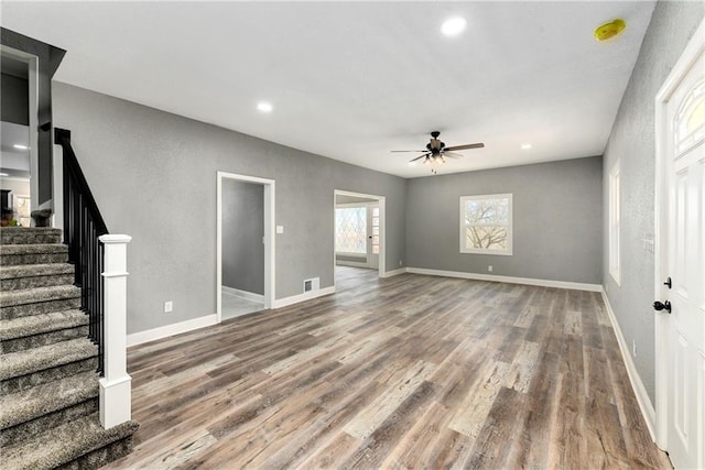 unfurnished living room featuring a ceiling fan, wood finished floors, recessed lighting, stairway, and baseboards