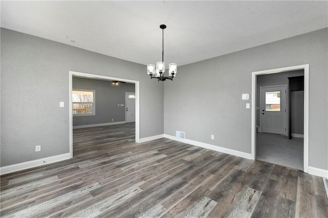 unfurnished dining area with visible vents, baseboards, an inviting chandelier, and wood finished floors