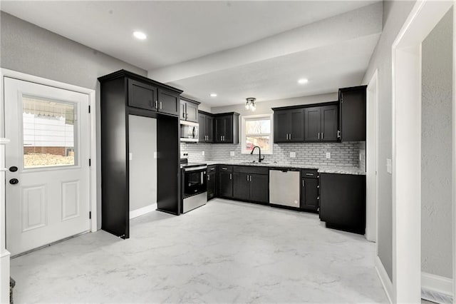 kitchen with a sink, decorative backsplash, appliances with stainless steel finishes, marble finish floor, and dark cabinets