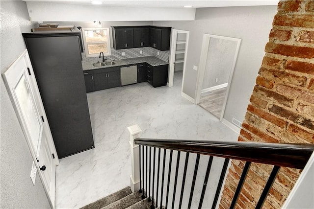 interior space with dark cabinetry, a sink, marble finish floor, stainless steel dishwasher, and tasteful backsplash