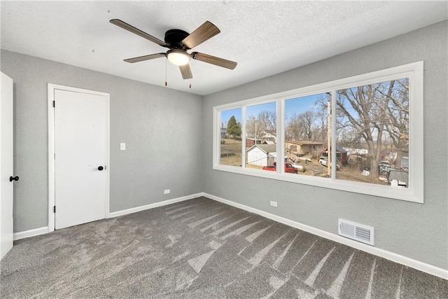 unfurnished bedroom featuring visible vents, a textured ceiling, carpet, baseboards, and a textured wall