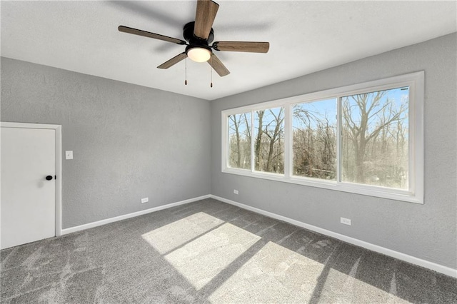 empty room featuring dark carpet, baseboards, and a textured wall