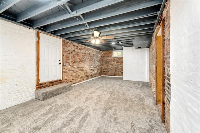 below grade area with carpet flooring, brick wall, and a ceiling fan