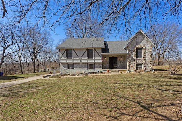 tudor house with brick siding, a shingled roof, and a front lawn