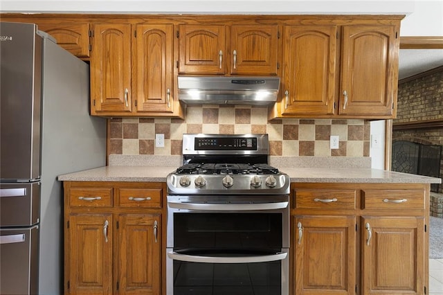 kitchen featuring light countertops, brown cabinetry, under cabinet range hood, and stainless steel appliances