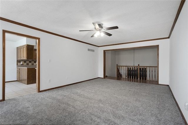 empty room with visible vents, light carpet, ceiling fan, and ornamental molding