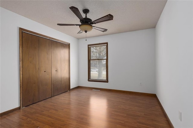 unfurnished bedroom with visible vents, wood finished floors, a closet, and a textured ceiling