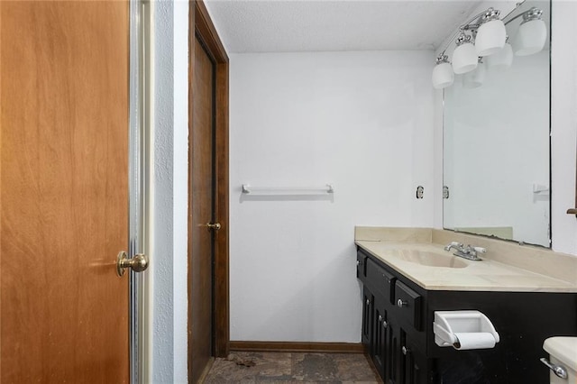 bathroom with toilet, vanity, and baseboards