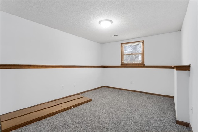 carpeted spare room featuring visible vents, baseboards, and a textured ceiling