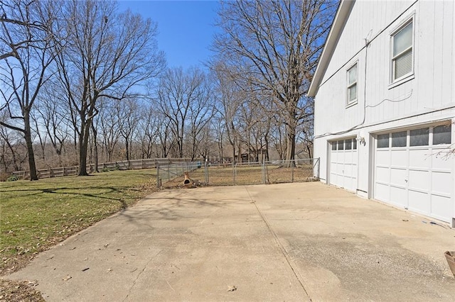 view of yard with driveway, a garage, and fence